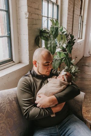 Family portrait session near windows with lush green plants in background.