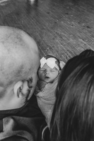Close-up black and white photo of parent and swaddled baby in intimate moment.