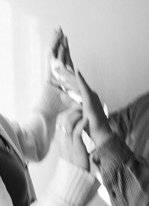 Abstract black and white motion blur photo of hands reaching towards each other.