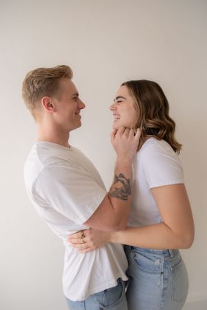 Intimate couple portrait against neutral background in casual white t-shirts and jeans.