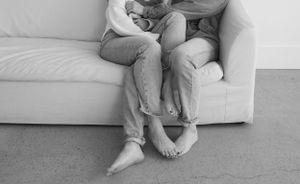 Minimalist black and white photo of couple sitting close together on a sofa.