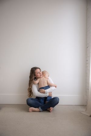 Intimate portrait against white wall in minimalist setting.