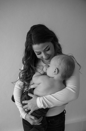 Tender embrace captured in black and white against plain wall.