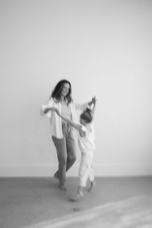 Blurred motion capture of dancing figures in white against grey background.