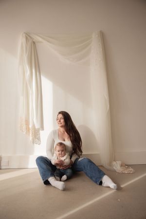 Minimalist portrait in white room with draped fabric and natural lighting.
