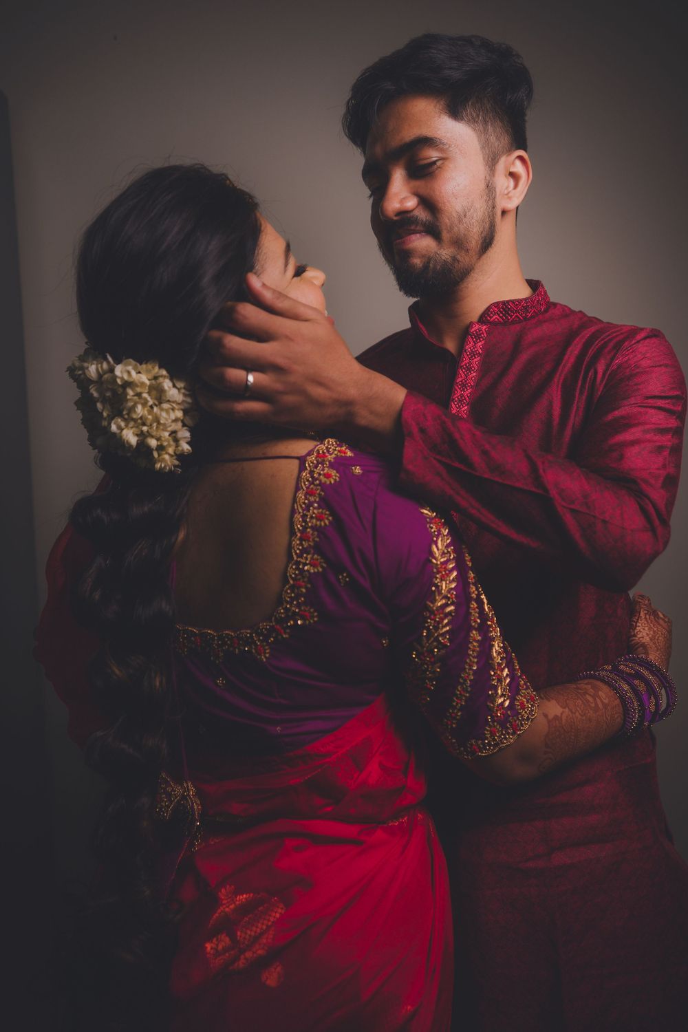 Romantic couple in traditional Indian wedding attire embracing in dramatic lighting.