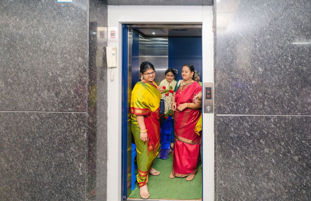 Traditional wedding guests in colorful saris stand in an elevator during a celebration.