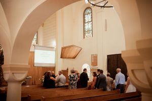 Interior view of a church during a ceremony showing arched ceilings and stained glass windows.