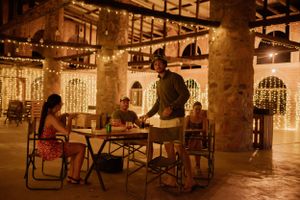 Evening gathering at rustic venue with string lights and stone columns.