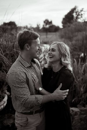Candid black and white photo of couple laughing together outdoors.