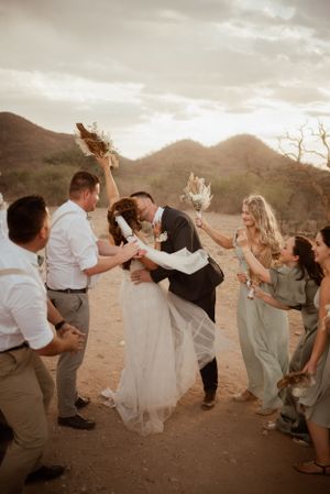 Wedding celebration with dancing and champagne toasts in desert setting at sunset.