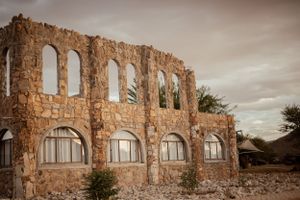 Ancient stone ruins with arched windows against moody desert sky.