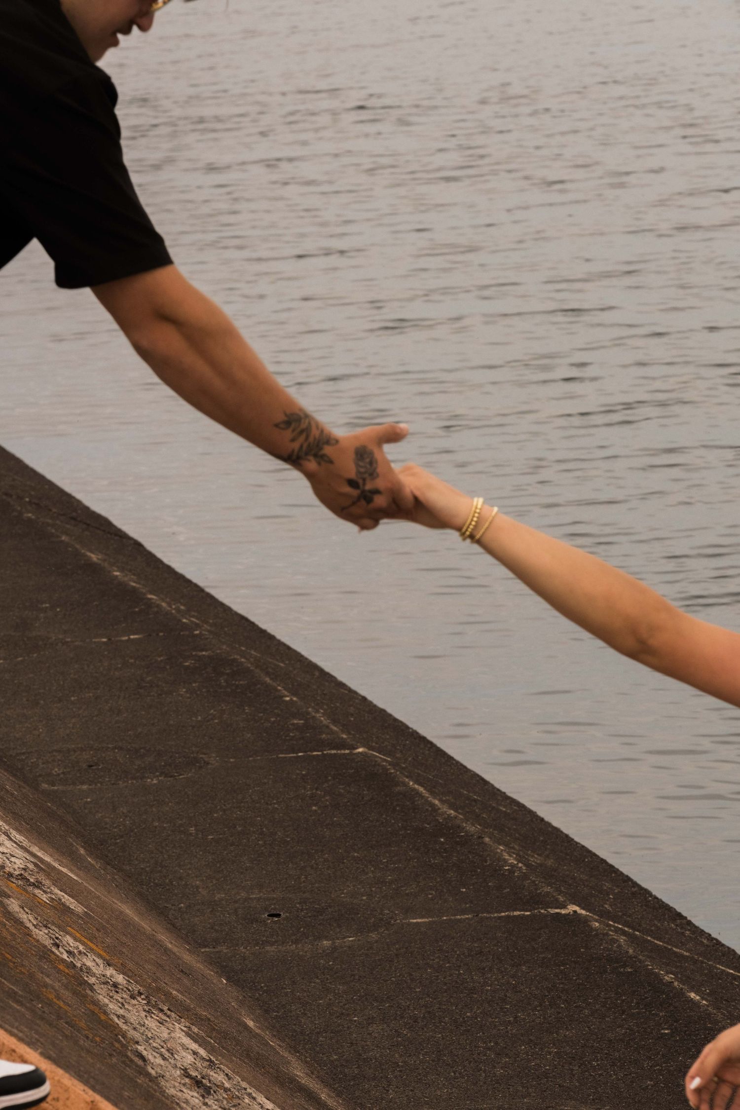 A detail shot of boyfriend offering a hand to his girlfriend who is down below