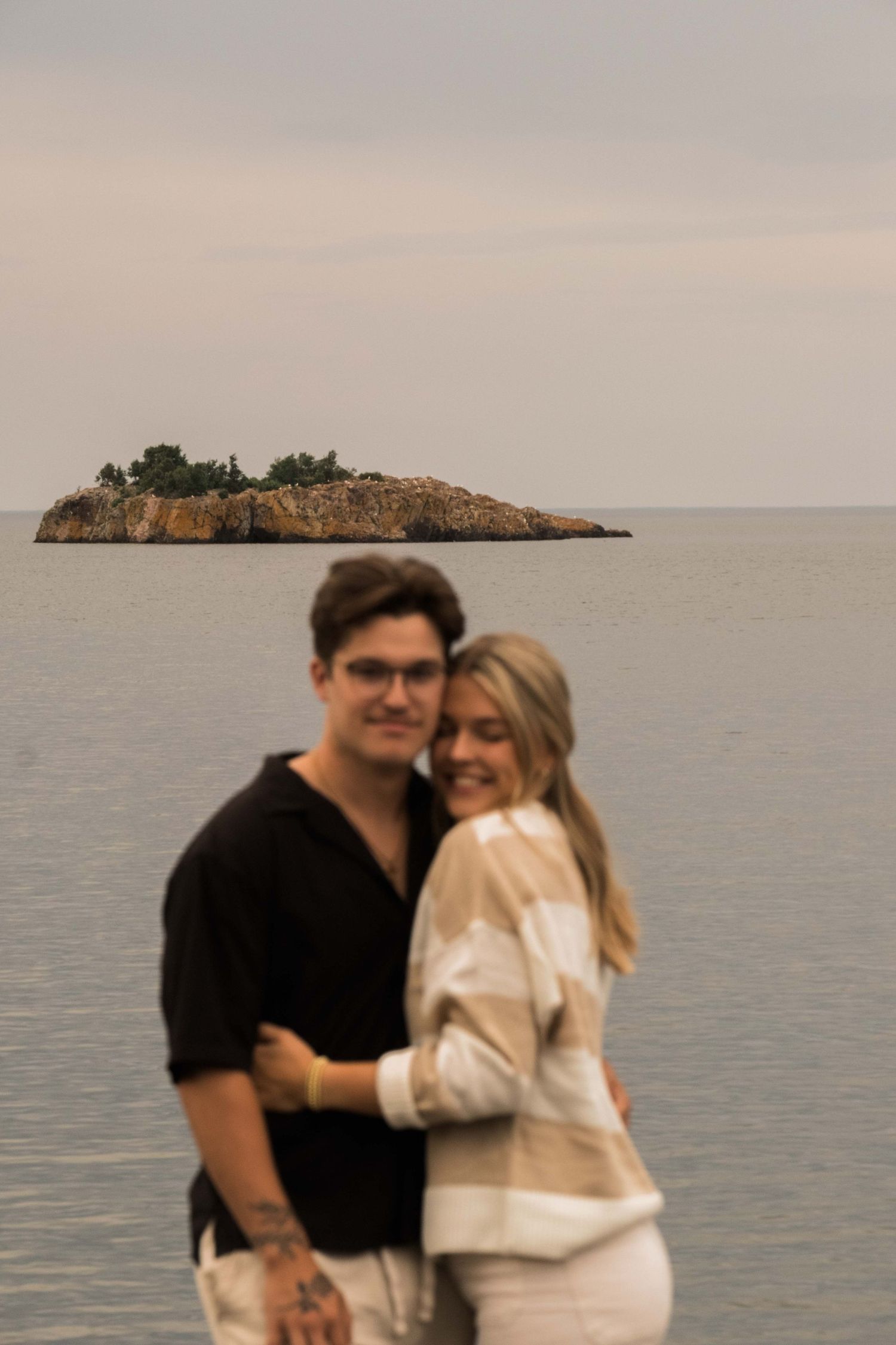 Shot of a couple with an island in the background, the island is in focus rather than the couple