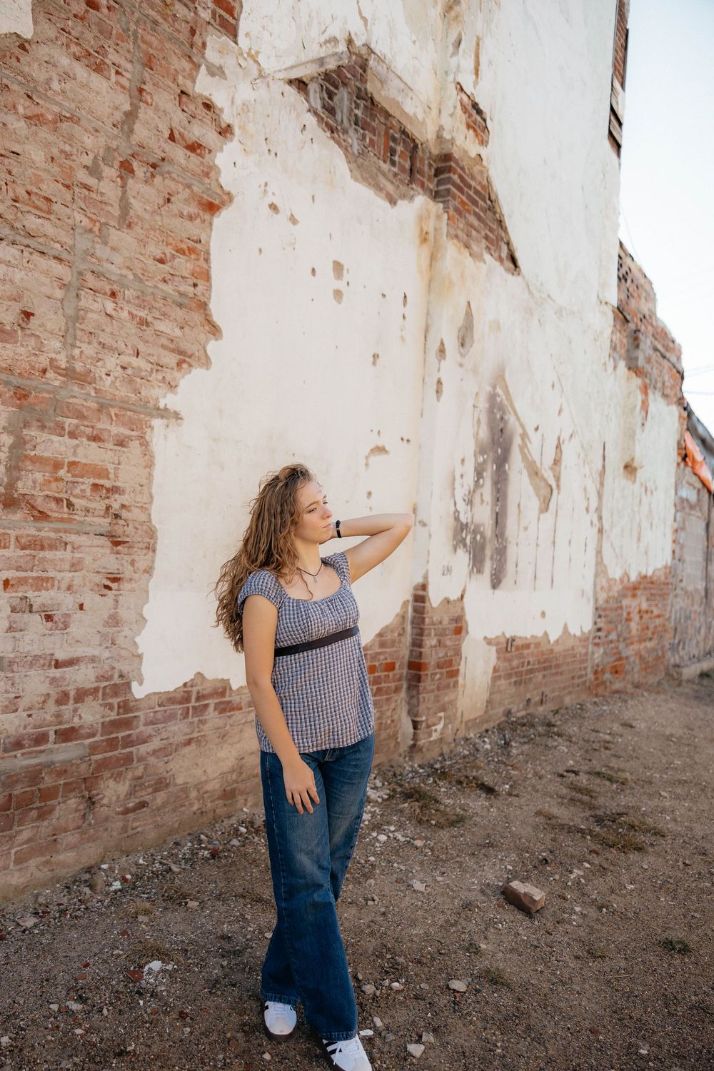Dynamic poses captured against distressed white and brick wall in urban setting.