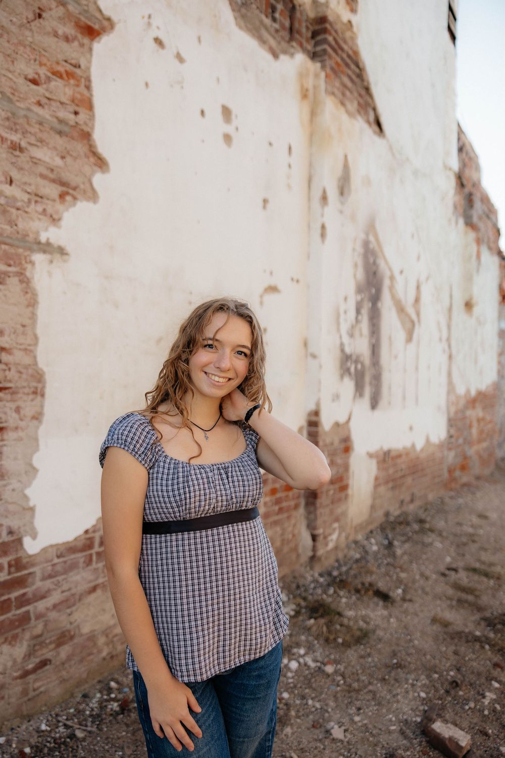 Lifestyle portraits against rustic brick wall backdrop with natural expressions and casual attire.