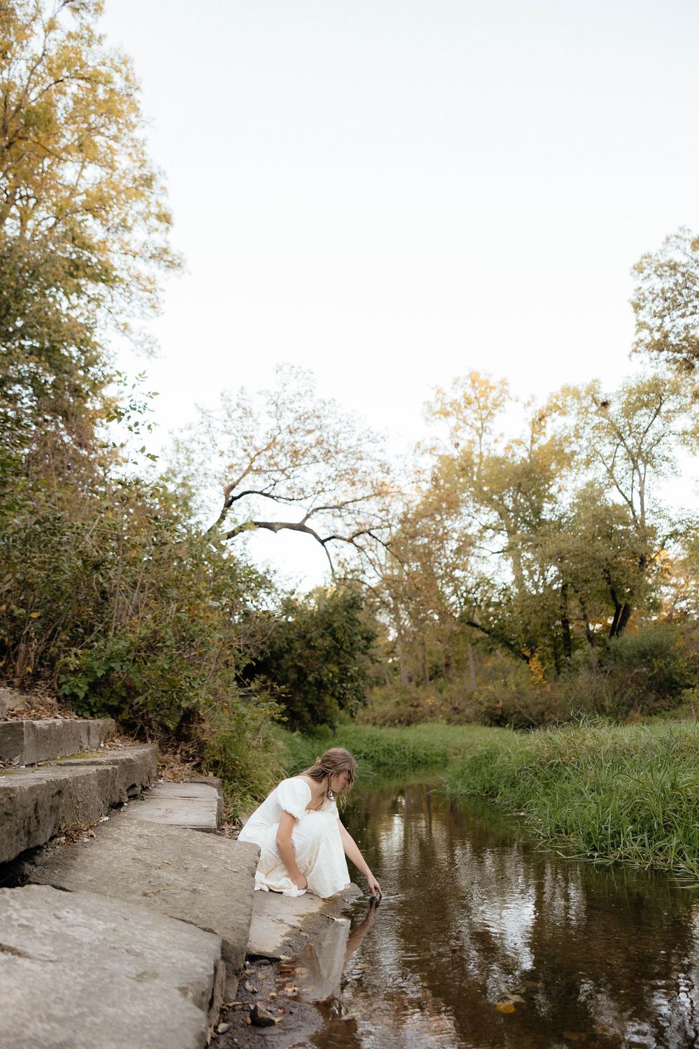 A serene autumn scene by a pond with trees and natural light filtering through the branches.