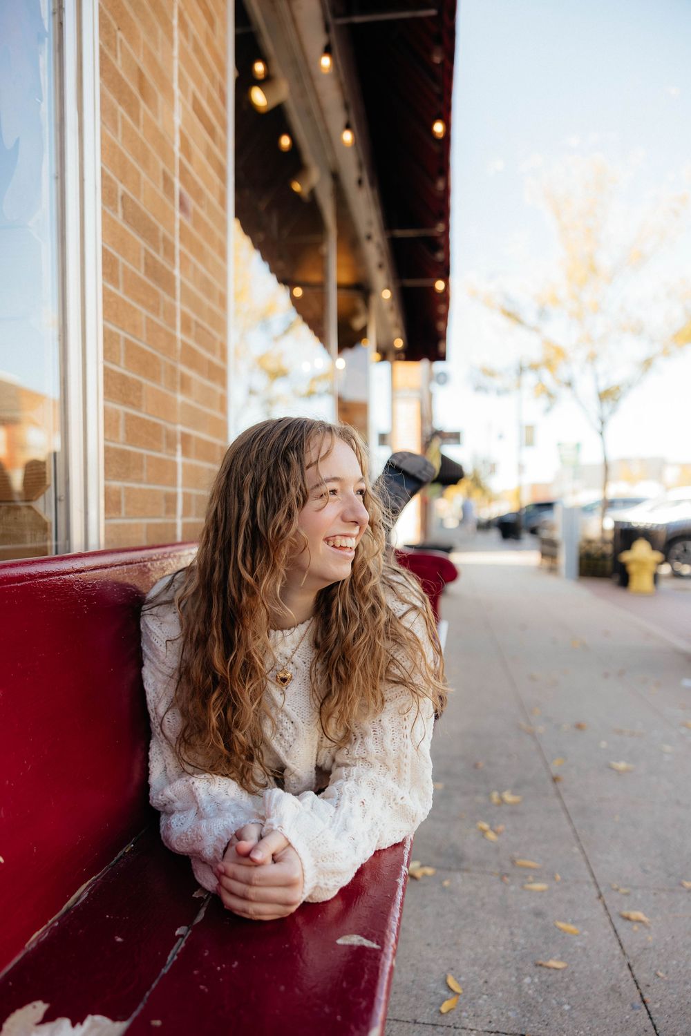A series of candid portraits showing someone in a white lace top sitting against a red bench outdoors.