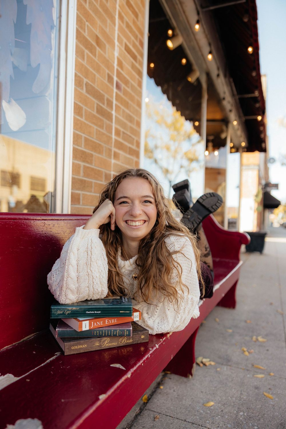 A series of candid shots showing someone lying on a red bench with books while wearing a cream sweater.