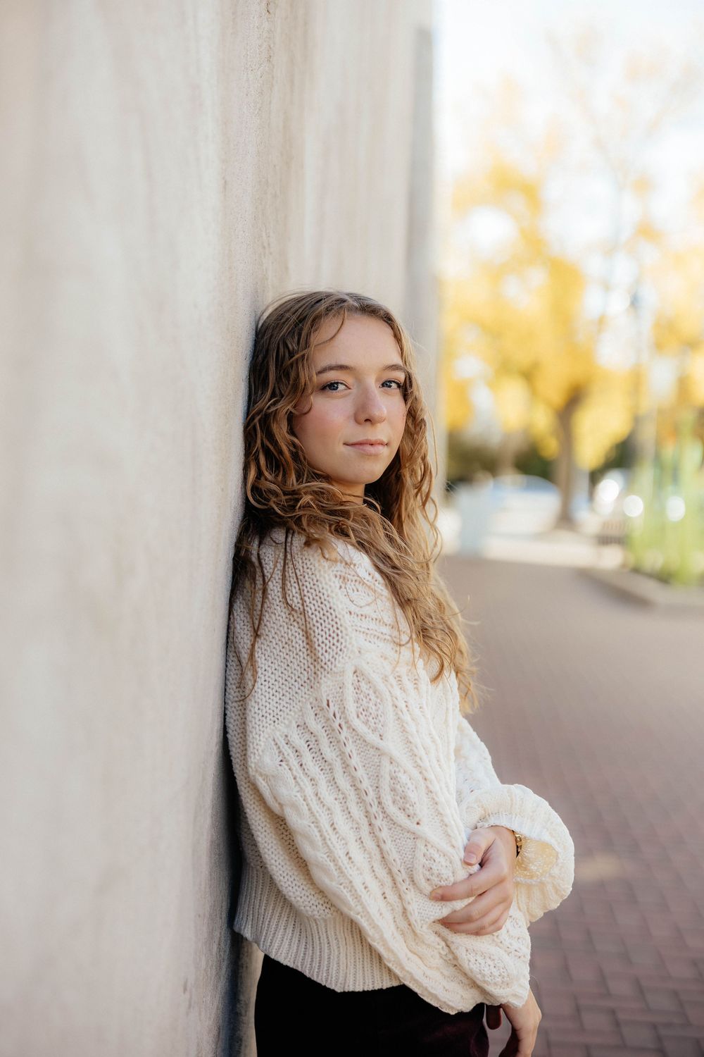 A collection of artistic portraits featuring someone in a cozy white sweater against a light colored wall.