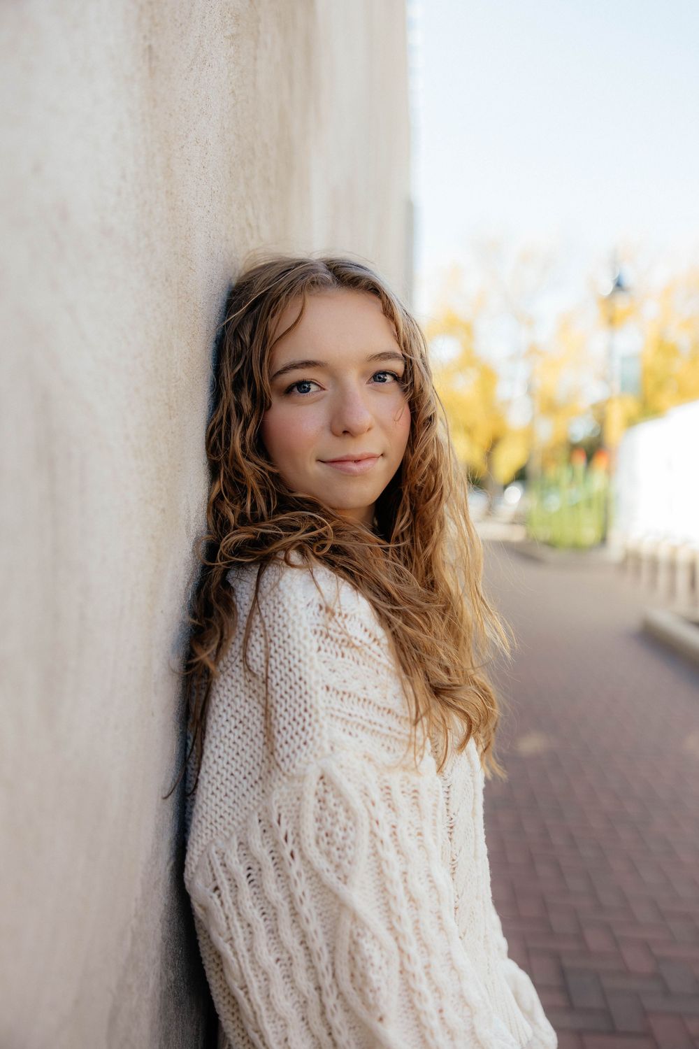 Portrait series against a white wall showing playful expressions in a cozy cream sweater.