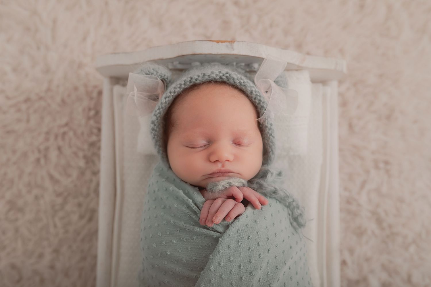 Peaceful newborn sleeping in mint wrap on textured cream backdrop. Photographer. Hull. East Yorkshire. Photography