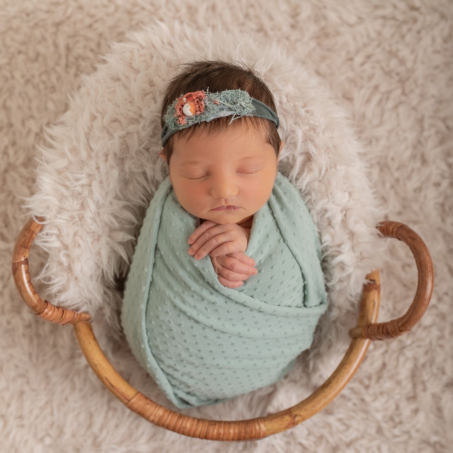Sleeping newborn wrapped in mint green swaddle with headband lying in curved wooden basket. Photographer. Hull. East Yorkshire. Photography
