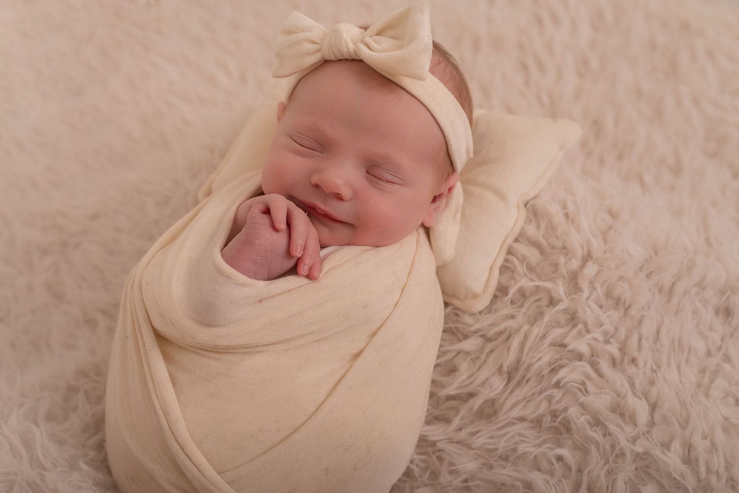 Sleeping newborn baby wrapped in cream colored swaddle on soft furry backdrop. Photographer. Hull. East Yorkshire. Photography