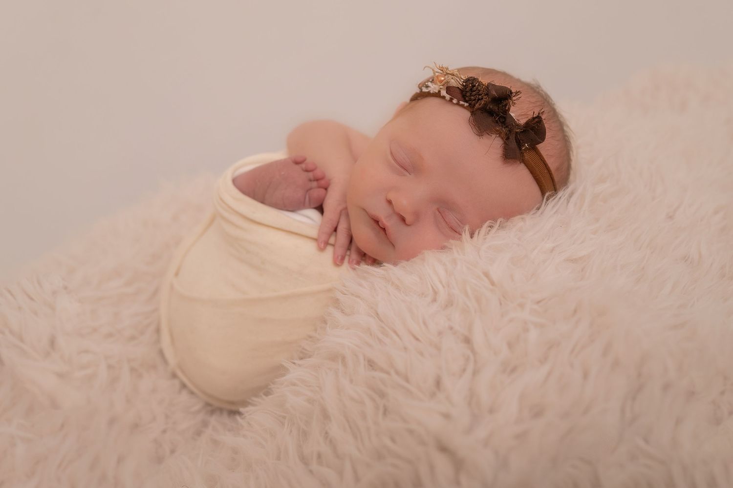 Sleeping newborn baby in cream wrap posed on textured white background. Photographer. Hull. East Yorkshire. Photography