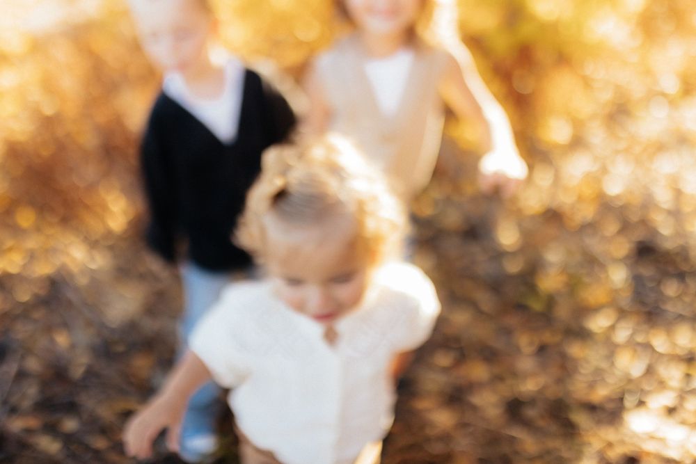A blurred motion photo of people walking through autumn foliage with golden bokeh lighting in the background.