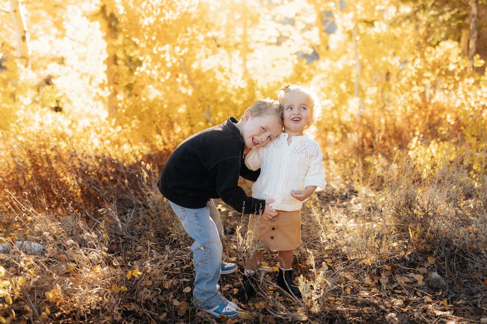 Two people share a tender moment in a golden autumn field during sunset.