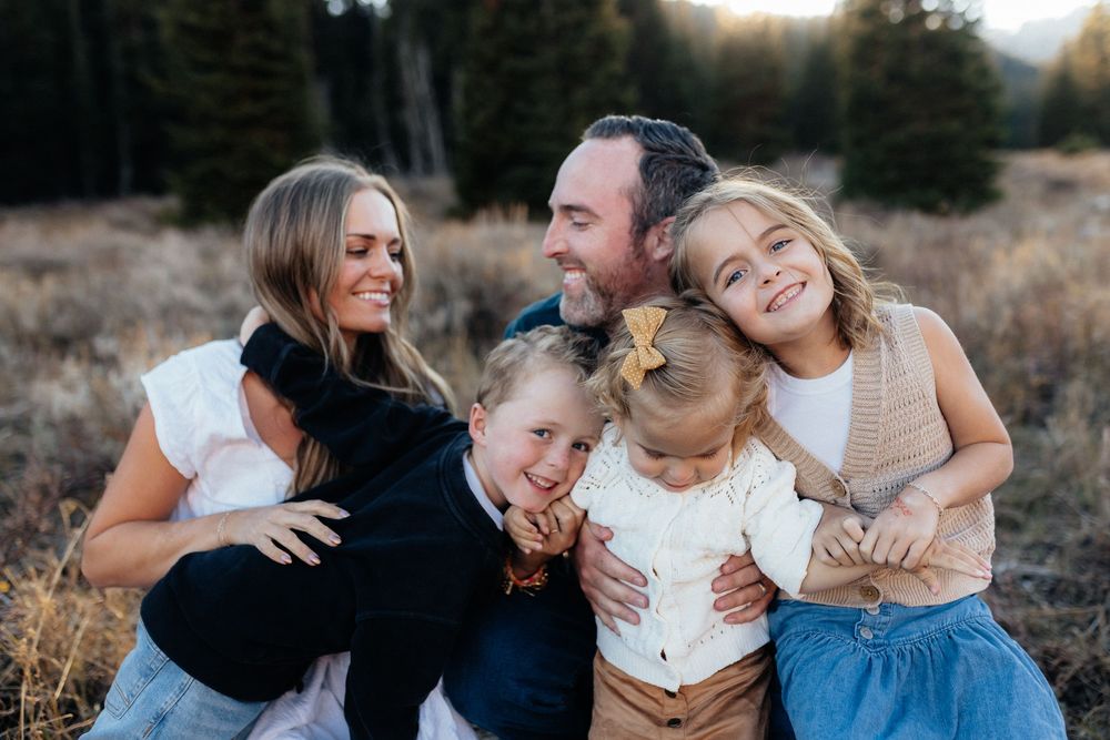 A loving family shares tender moments together in a golden sunlit field during an outdoor photo session.