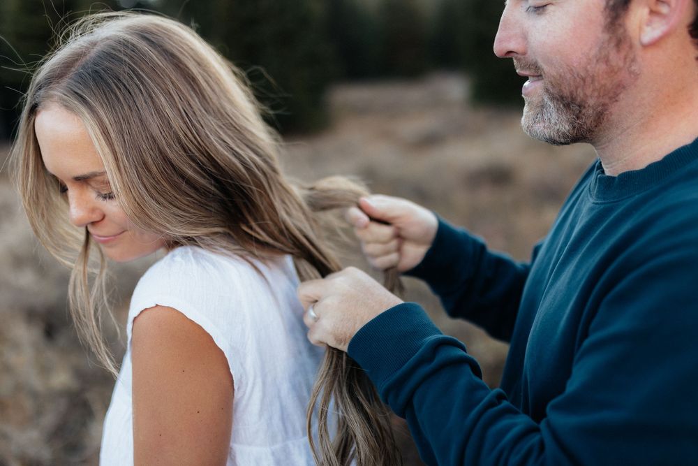A couple stands close together during an intimate outdoor photoshoot at sunset.