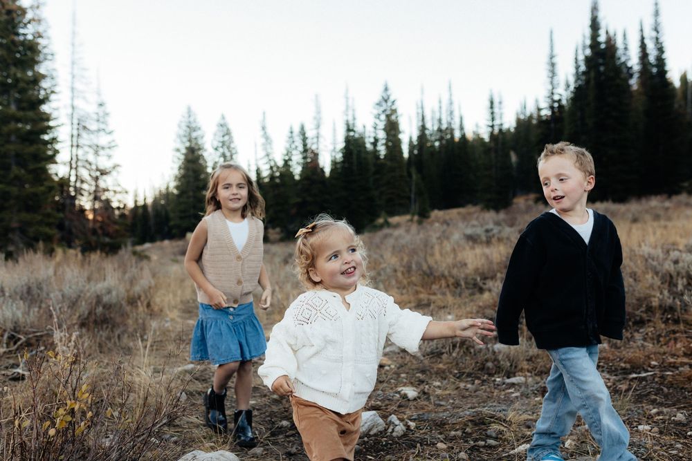 Family enjoying a playful moment together in a rustic outdoor setting during golden hour.