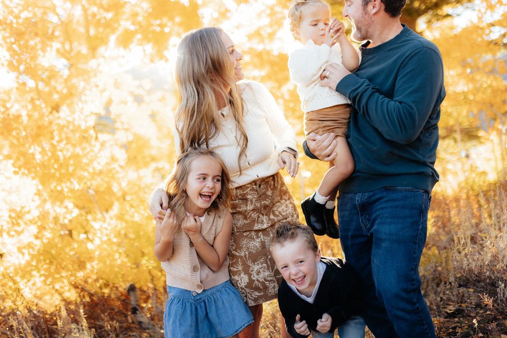 A family enjoys playful moments together in a golden autumn field during sunset.