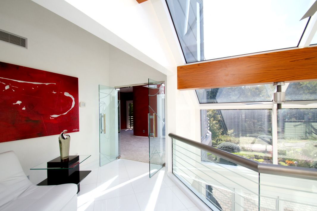 Modern interior design with red accent wall and glass balcony overlooking bright space.