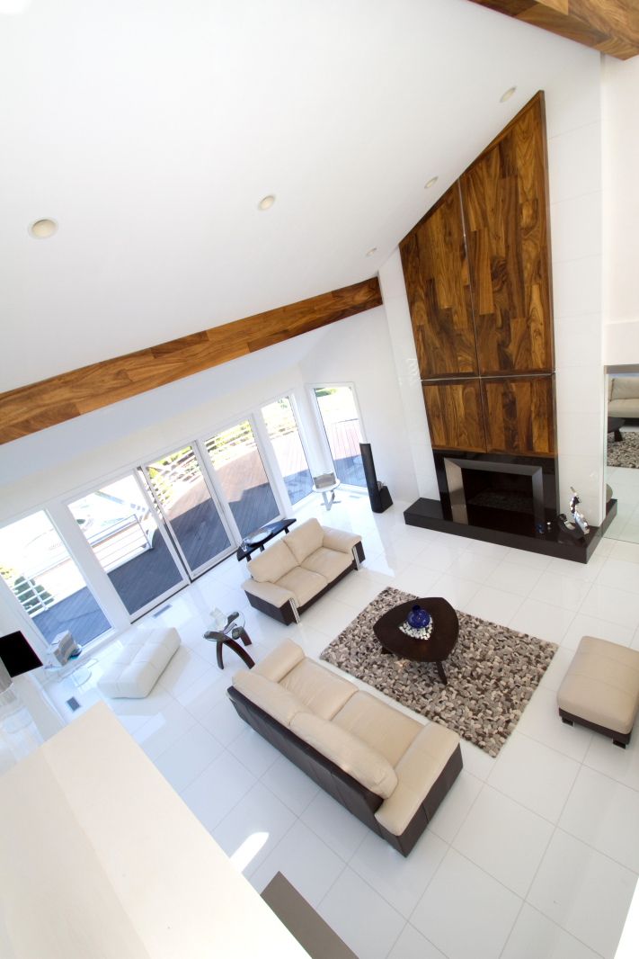 Modern living room with vaulted ceiling, wooden beams and contemporary white furniture.