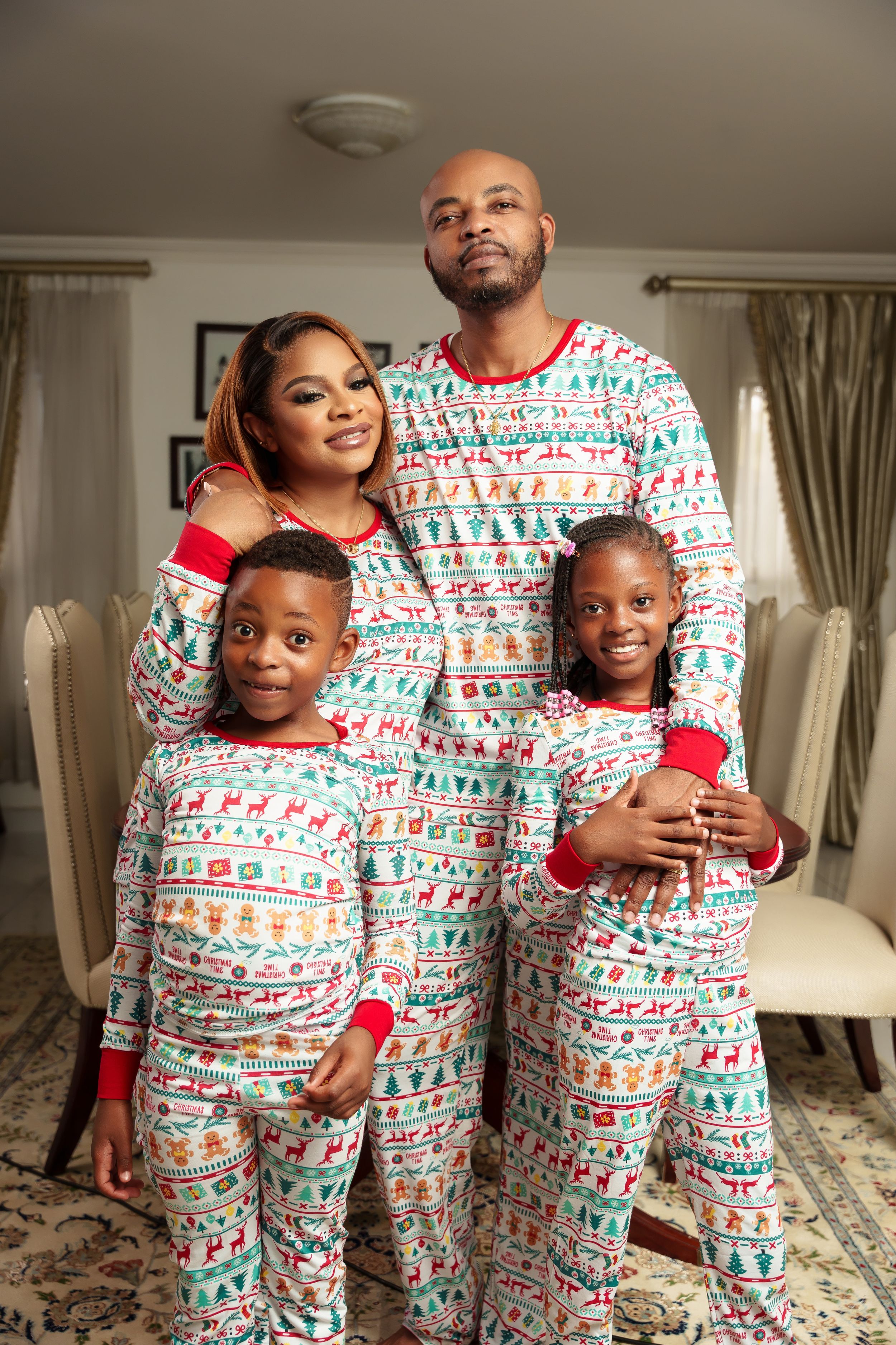 Family wearing matching holiday pajamas poses together in living room.