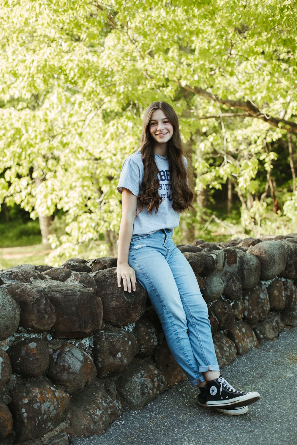 Casual outdoor portrait session along stone wall with natural lighting.