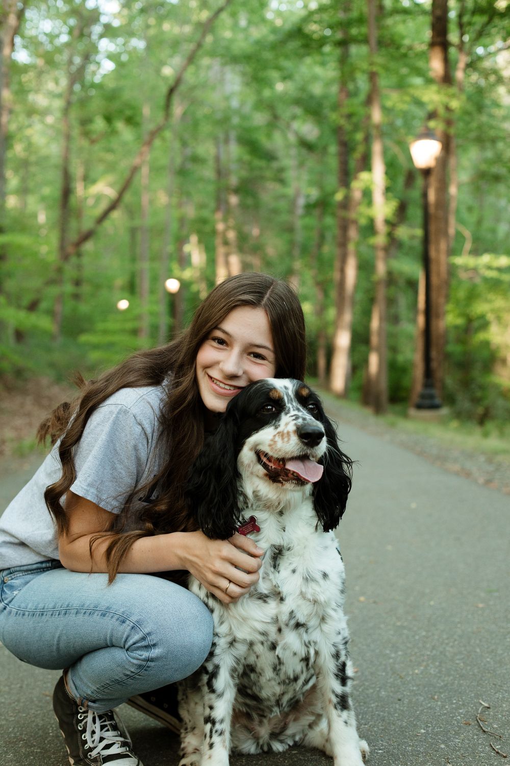 A sweet moment between a person and their black and white dog on a wooded path.