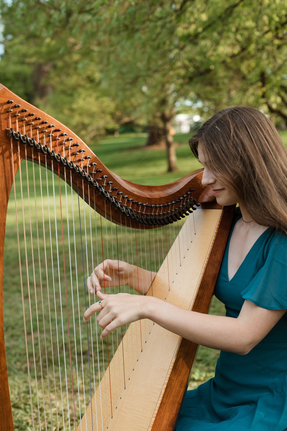 Close-up shots of hands playing a wooden Celtic harp outdoors.