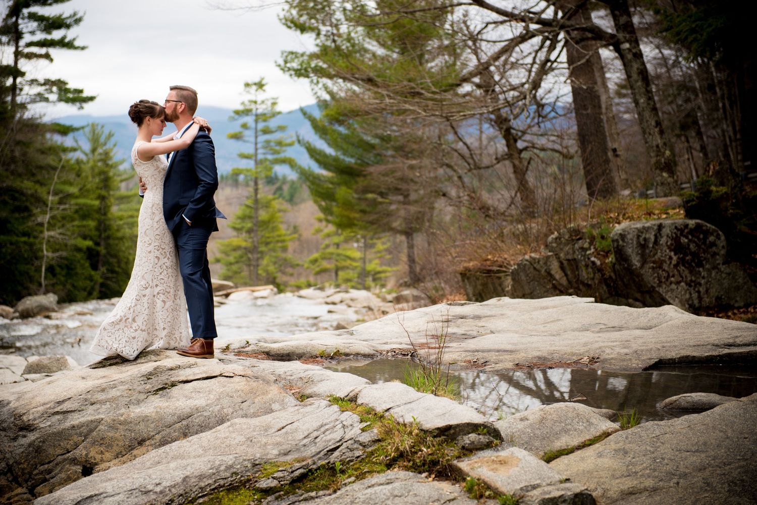 Romantic photoshoot on rocky mountain ledge surrounded by pine trees and scenic views.