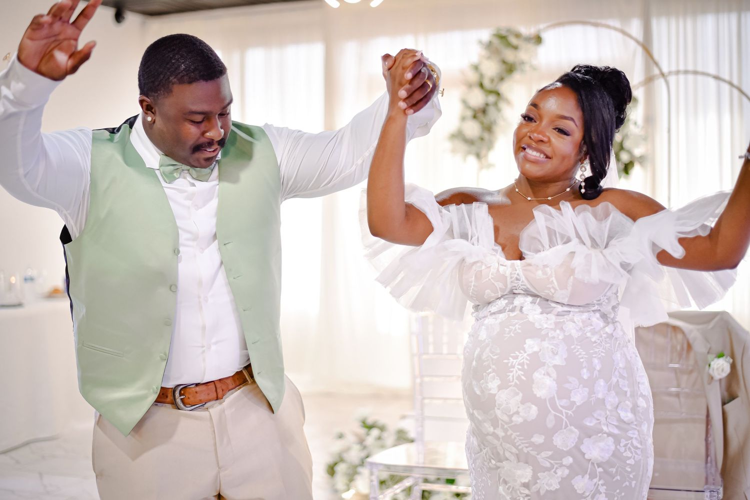 Joyful wedding couple dancing and celebrating in white dress and mint green vest.