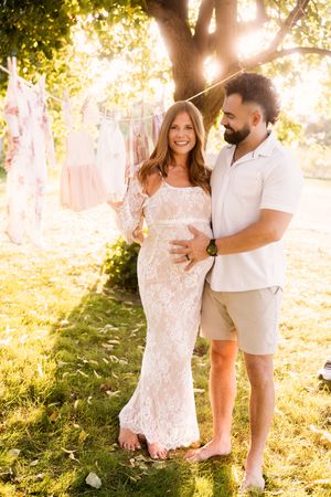 Joyful family portrait captured in golden sunlight with trees and greenery in background.