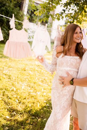 Couple embraces in a sunlit garden with hanging laundry on clotheslines in the background.