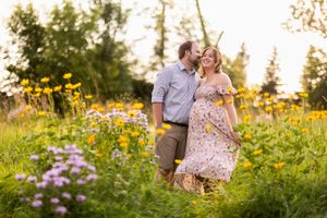 Couple shares tender embrace surrounded by vibrant wildflowers in golden summer meadow at sunset.