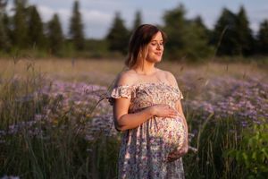 Person in floral dress walking through a golden sunset field of blooming lavender and wildflowers.