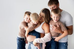 A family wearing white and denim embraces in a tender moment during a studio photography session.