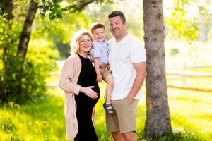 Couple shares tender moments in a sun-dappled wooded area during a photography session.