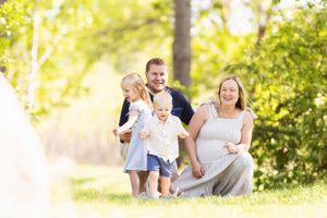 A family enjoys a sunlit moment together outdoors in a natural setting with trees and golden lighting.